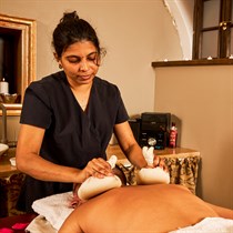 Masažas su šiltais žolelių ryšulėliais